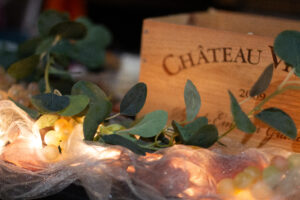 Vines and string lights laid out on a tule-covered table with a wine box in the background.
