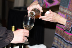 Close up of hands pouring wine into a wine glass.